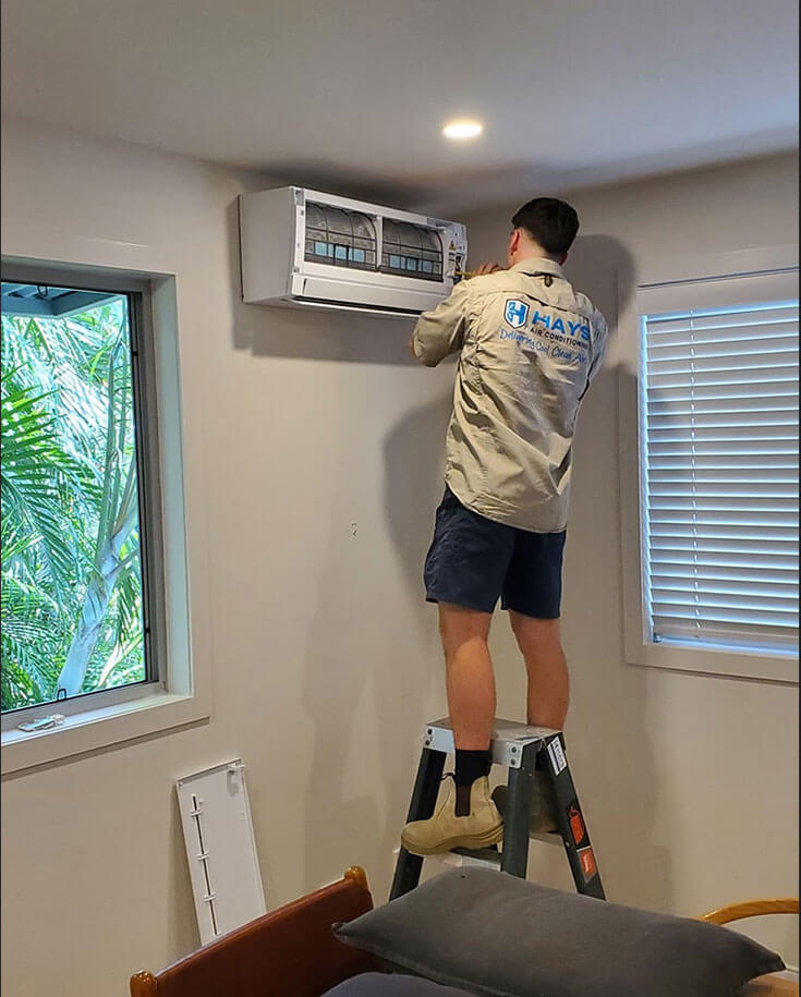 Technician performing split system cleaning on the wall unit