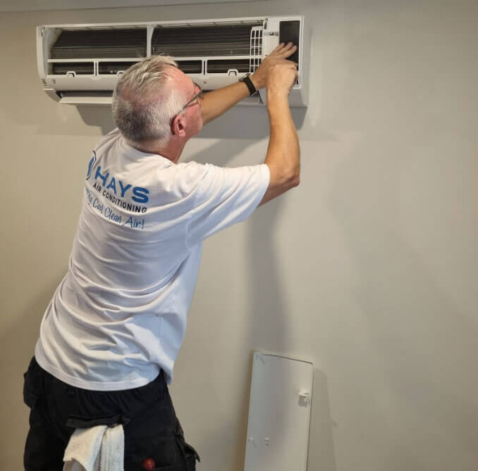Technician performing professional deep cleaning on a split system air conditioner in a Redcliffe home.